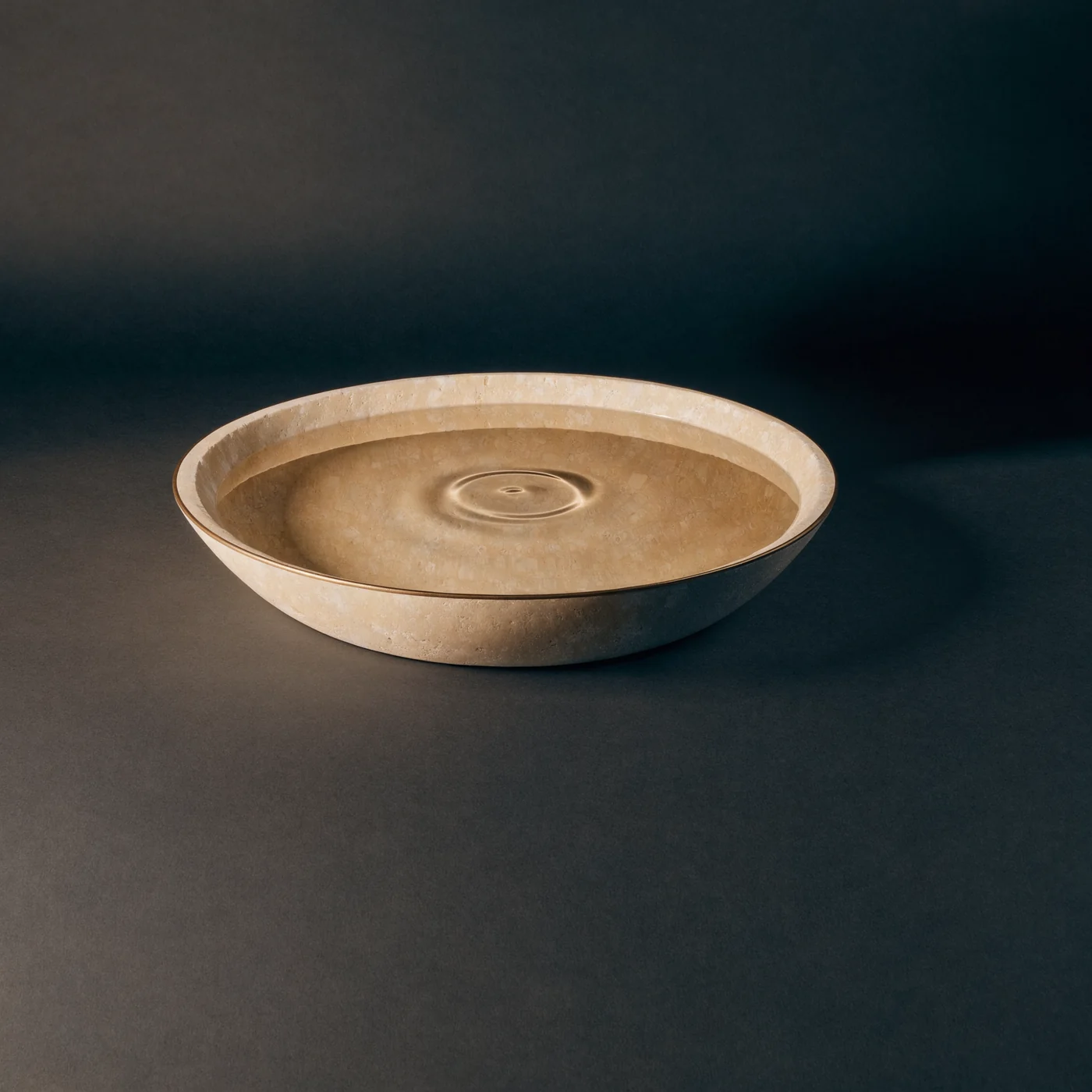 A single ripple spreads across water in a shallow limestone bowl.